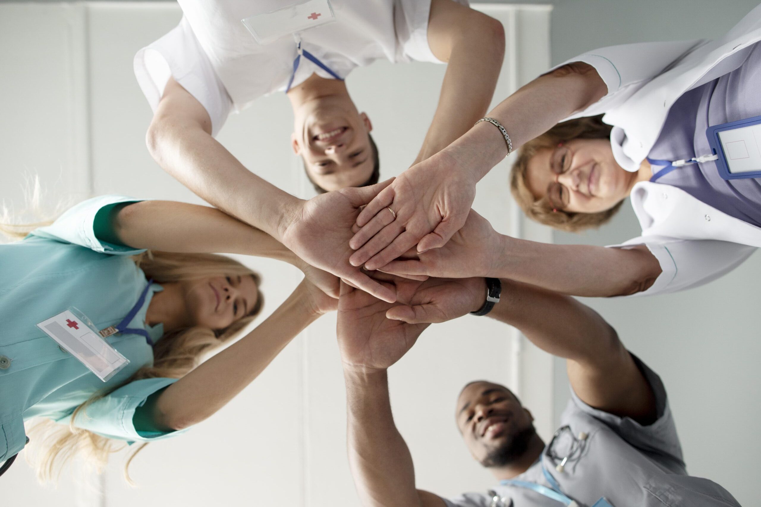 Gruppen von 4 Personen, die die Hände in der Mitte alle übereinander legen.